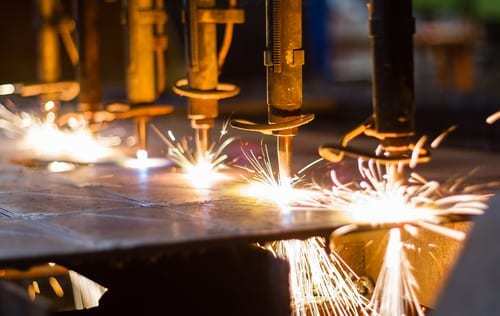 A closeup of a machine cutting steel with sparks